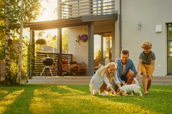 family playing in their backyard with their house behind them